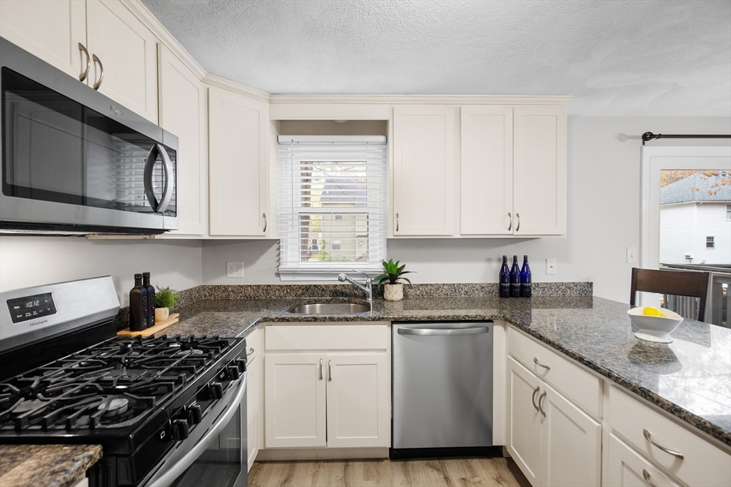 730 Wellman Avenue, Unit 730 Chelmsford, MA 01863 - Photo 12 of 31 a kitchen with stainless steel appliances granite countertop white cabinets and a stove top oven