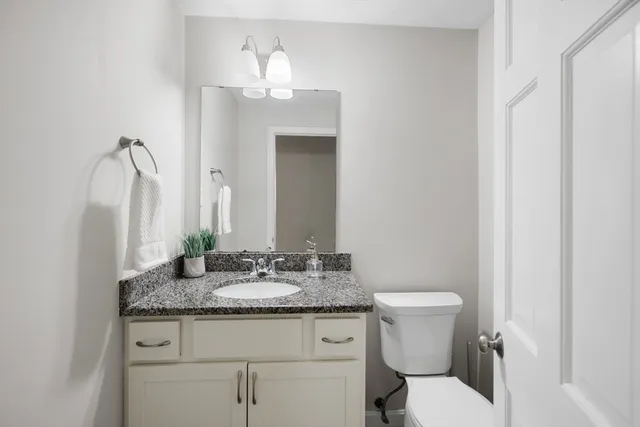 a bathroom with a granite countertop sink a toilet and a mirror