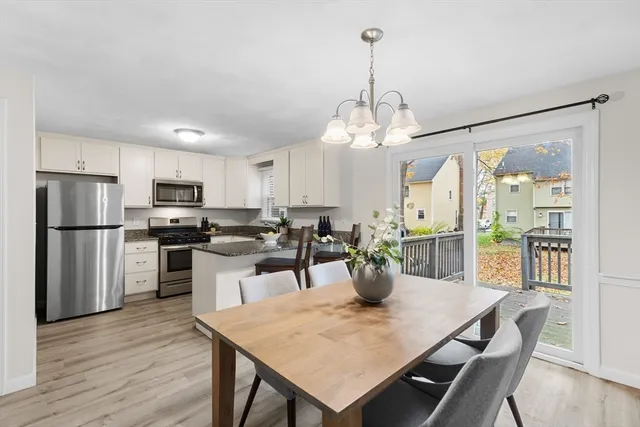 a view of a dining room and livingroom with furniture wooden floor a chandelier