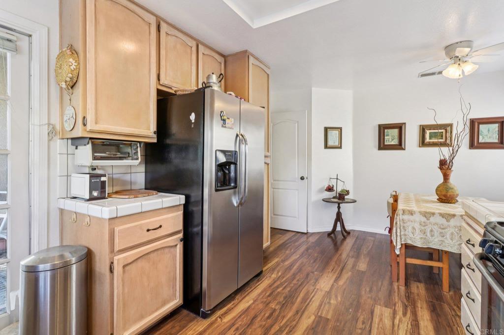 7747 Caminito Monarca, Unit 100 Carlsbad, CA 92009 - Photo 21 of 67 a kitchen with stainless steel appliances granite countertop a refrigerator a stove and a dining table with wooden floor