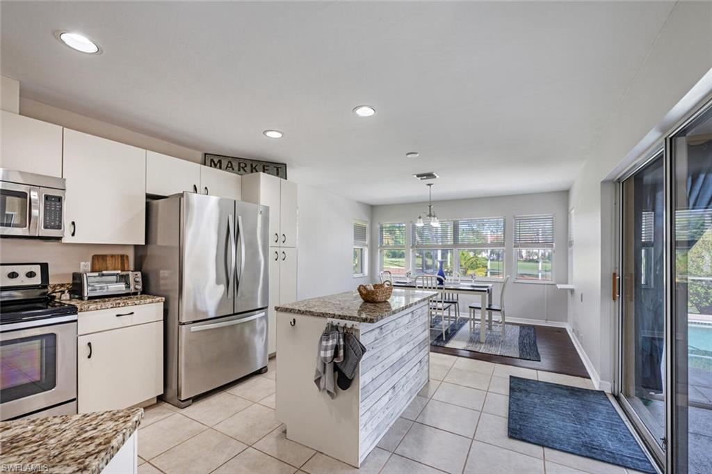 641 St Andrews Boulevard, Unit 1081 Naples, FL 34113 - Photo 12 of 31 a kitchen with granite countertop a refrigerator and a stove top oven