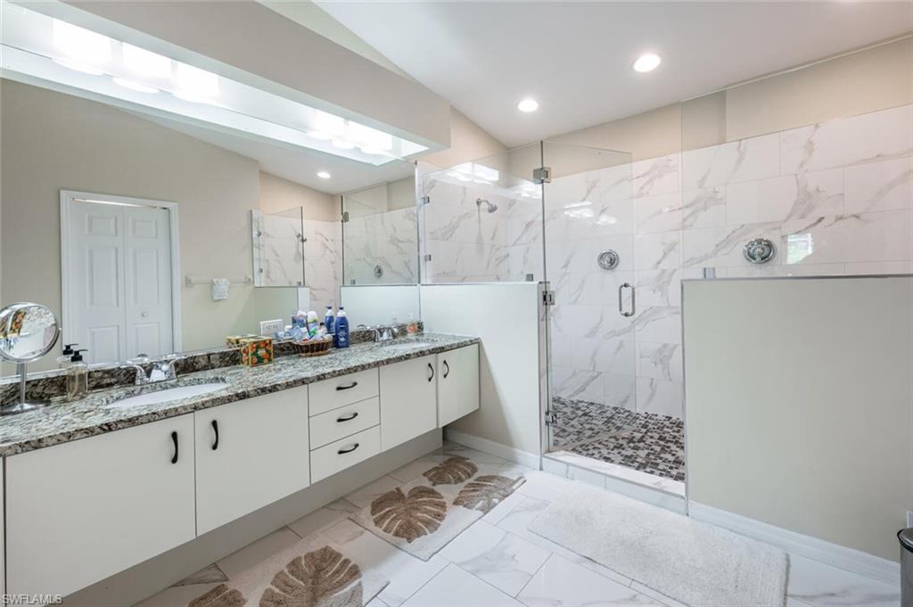 641 St Andrews Boulevard, Unit 1081 Naples, FL 34113 - Photo 21 of 31 a bathroom with a granite countertop sink a mirror a toilet and shower