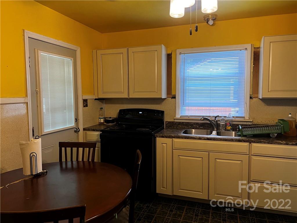 196 London Road Asheville, NC 28803 - Photo 4 of 14 a kitchen with granite countertop a sink a stove cabinets and a dining table