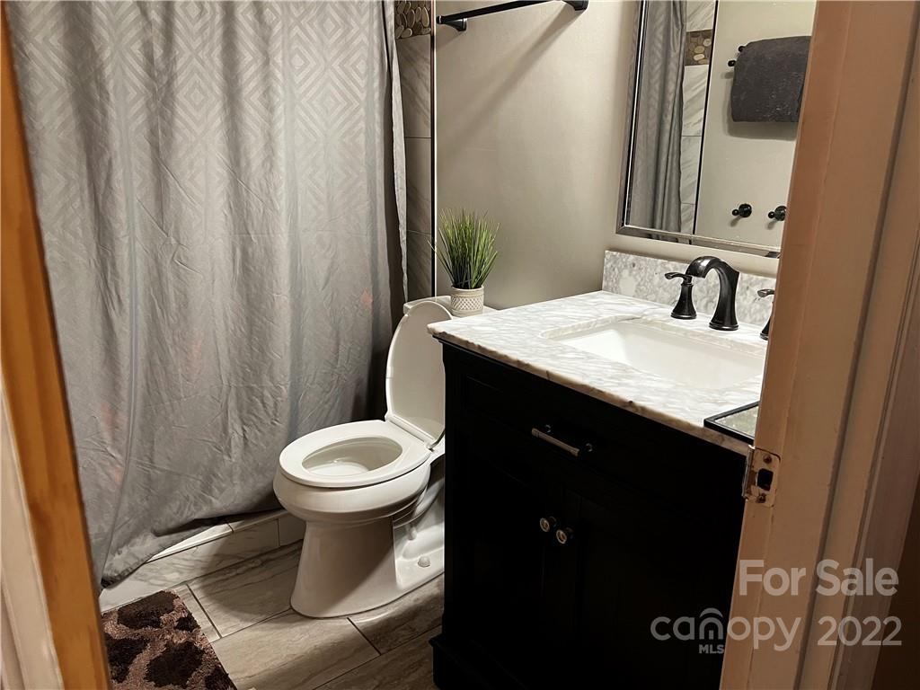 196 London Road Asheville, NC 28803 - Photo 8 of 14 a bathroom with a granite countertop sink toilet and mirror