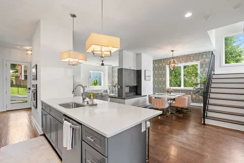 a kitchen with stainless steel appliances a stove a sink a center island and couches