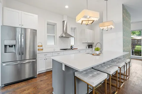 a kitchen with granite countertop a stove a refrigerator and a dining table