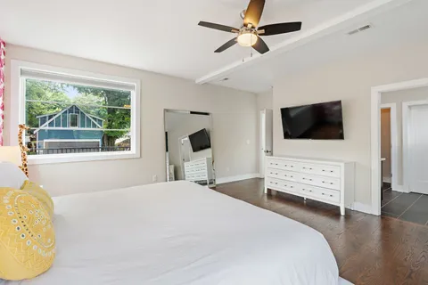 a bedroom with a bed a flat screen tv and a large window