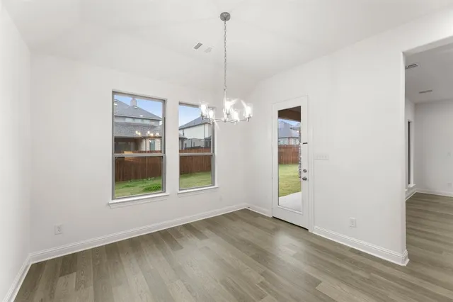 a view of a room with wooden floor chandeliers and kitchen view