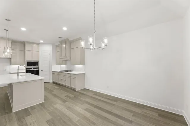 a large kitchen with granite countertop a white stove top oven and white cabinets
