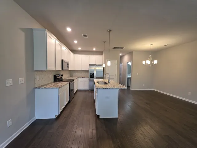 a kitchen with granite countertop a sink a counter top space and cabinets