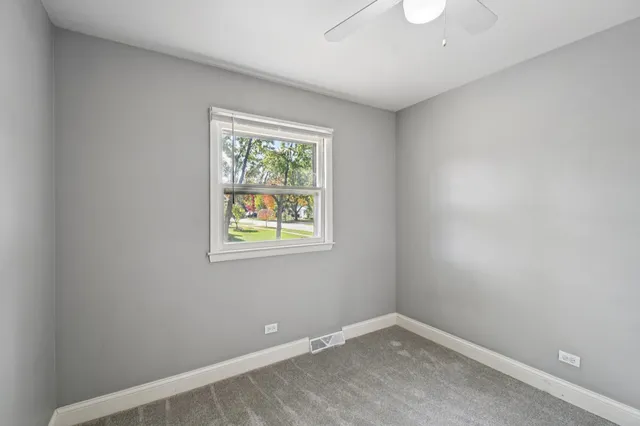 an empty room with closet and a chandelier fan