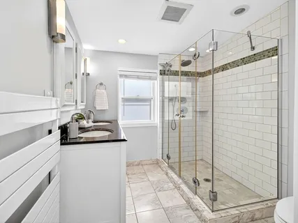 a bathroom with a granite countertop sink a mirror and shower