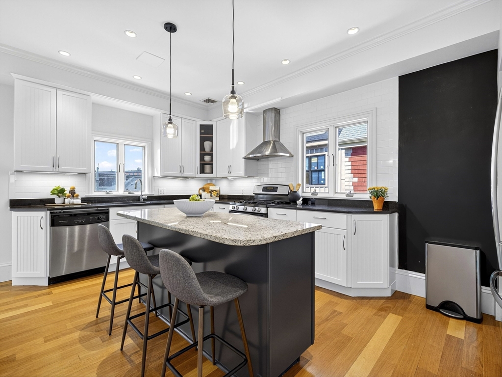 24 Evergreen Street, Unit 2 Boston, MA 02130 - Photo 9 of 31 a kitchen with stainless steel appliances granite countertop a sink a stove a refrigerator and island with wooden floor