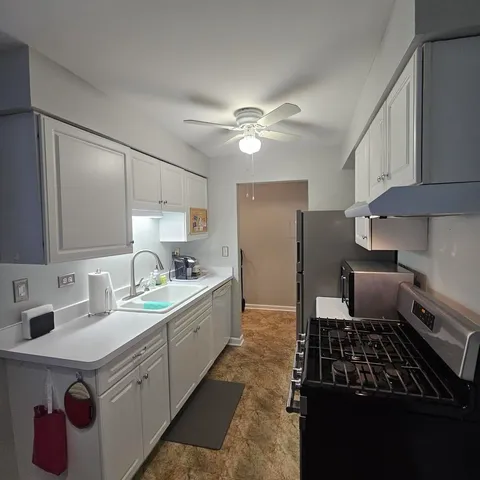 a kitchen with kitchen island granite countertop a sink appliances cabinets and a counter top space