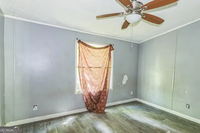 an empty room with wooden floor fan and windows