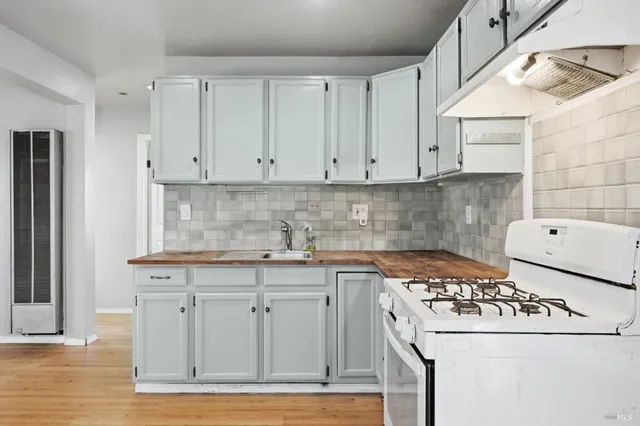 a view of an empty room with wooden floor and windows