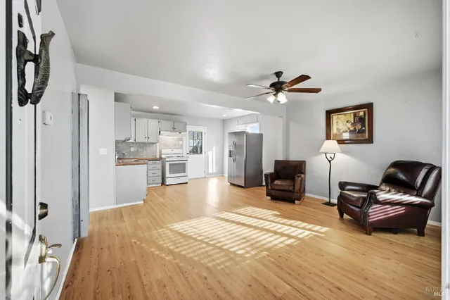 a view of a livingroom with furniture a ceiling fan and wooden floor