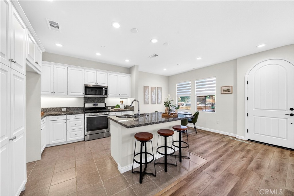 341 Adalina Lane Brea, CA 92821 - Photo 22 of 60 a kitchen with stainless steel appliances kitchen island granite countertop a stove a sink a refrigerator and white cabinets with wooden floor