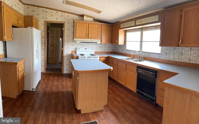 a kitchen with stainless steel appliances granite countertop wooden cabinets a refrigerator a sink a stove a microwave and wooden floors