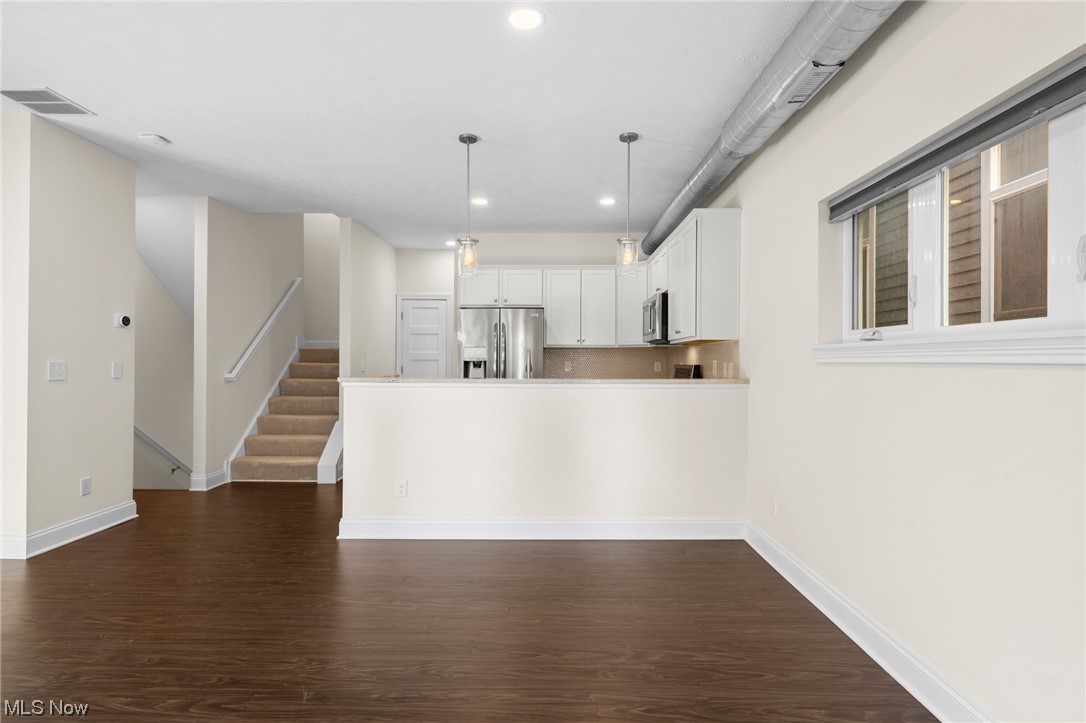 1943 Randall Road Cleveland, OH 44113 - Photo 16 of 40 Kitchen with white cabinetry, decorative light fixtures, stainless steel appliances, and dark hardwood / wood-style flooring