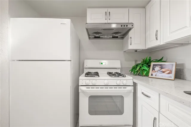 a kitchen with stainless steel appliances white cabinets and a refrigerator