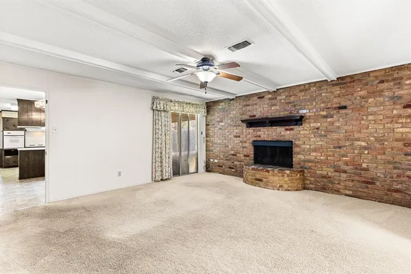 an empty room with chandelier fan and windows