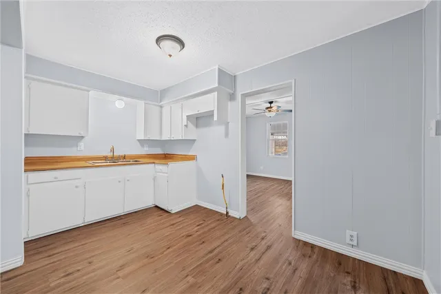 a kitchen with wooden floors and white cabinets