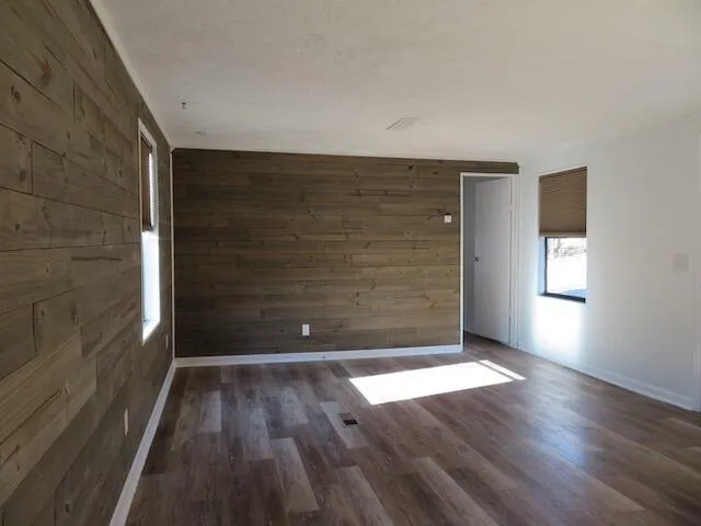 an empty room with wooden floor fan and windows