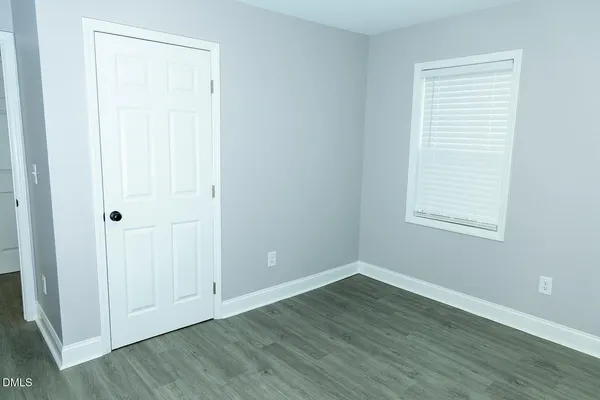 an empty room with wooden floor and window