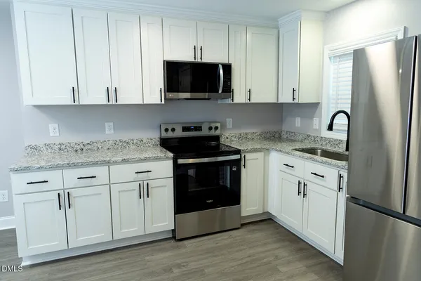 a kitchen with granite countertop white cabinets and stainless steel appliances