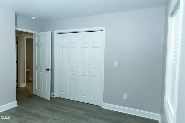 an empty room with wooden floor and closet area