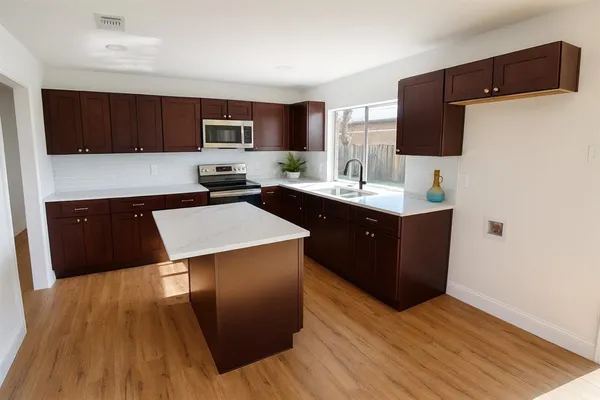 a kitchen with stainless steel appliances a sink cabinets and wooden floor
