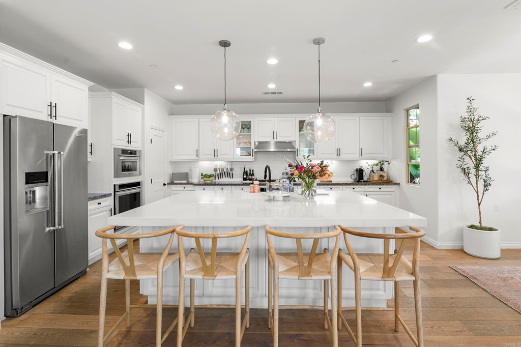 7001 Sitio Frontera Carlsbad, CA 92009 - Photo 12 of 40 a kitchen with stainless steel appliances kitchen island granite countertop a refrigerator a stove a kitchen island with a dining table and chairs