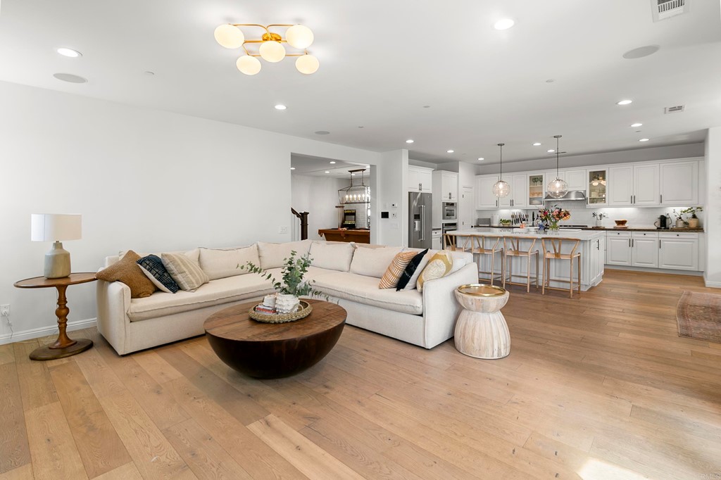 7001 Sitio Frontera Carlsbad, CA 92009 - Photo 17 of 40 a living room with furniture a chandelier and a view of kitchen
