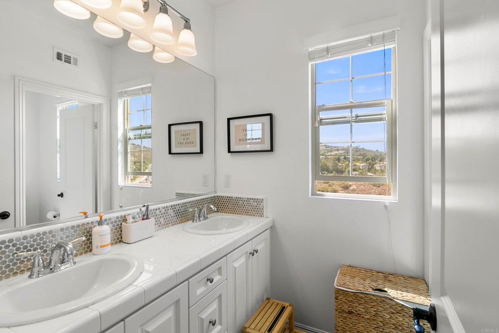 7001 Sitio Frontera Carlsbad, CA 92009 - Photo 20 of 40 a bathroom with a granite countertop sink a light fixture and a mirror