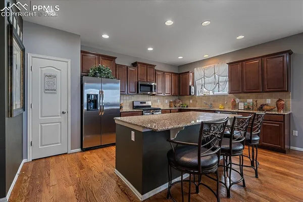a kitchen with stainless steel appliances granite countertop a table chairs sink refrigerator and cabinets