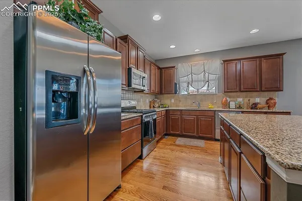 a kitchen with stainless steel appliances granite countertop a refrigerator a sink a stove and a oven