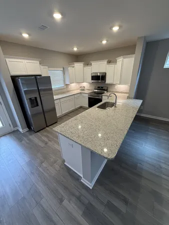 a large kitchen with stainless steel appliances granite countertop a large counter top and wooden floors