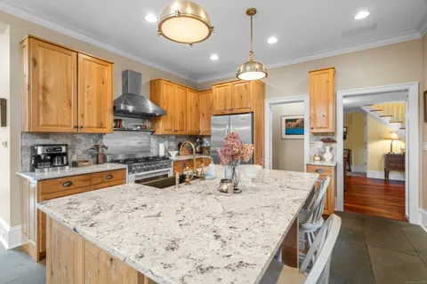 a kitchen with stainless steel appliances granite countertop wooden cabinets a stove top oven a sink a dining table and chairs