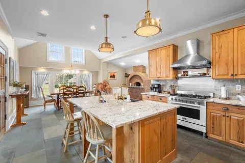 a kitchen with stainless steel appliances granite countertop a stove a sink dishwasher a dining table and chairs with wooden floor