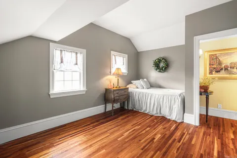 a bedroom with a bed wooden floor and window