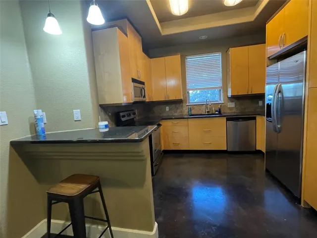 a kitchen with stainless steel appliances granite countertop a sink wooden cabinets and a granite counter tops