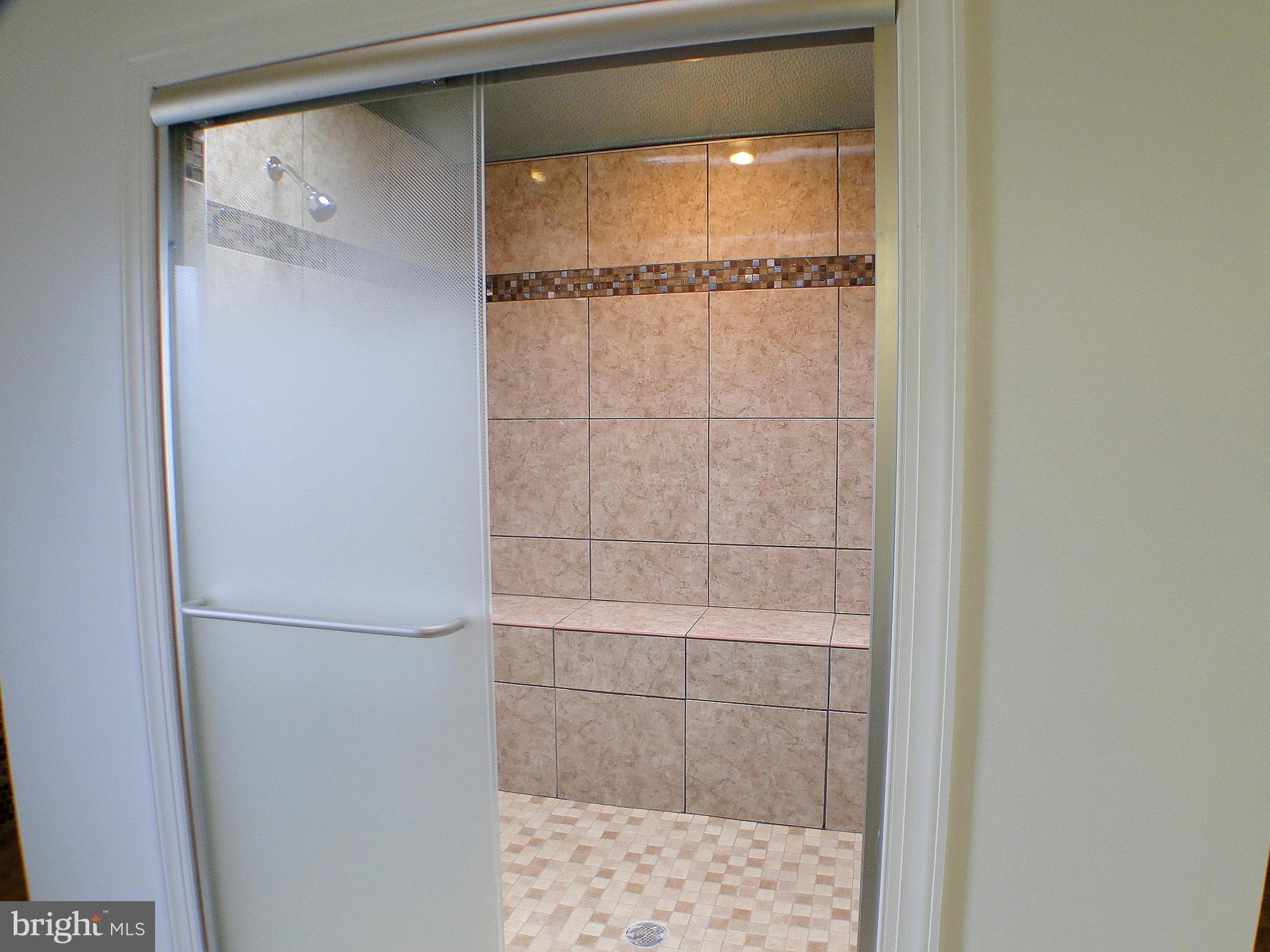 8232 Brattle Road Pikesville, MD 21208 - Photo 21 of 30 a bathroom with a glass shower door and a window