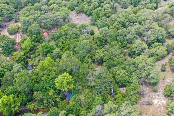 an aerial view of residential house with outdoor space and trees all around