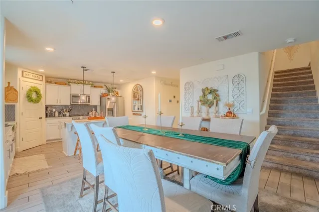 a kitchen with stainless steel appliances granite countertop a dining table chairs and a refrigerator