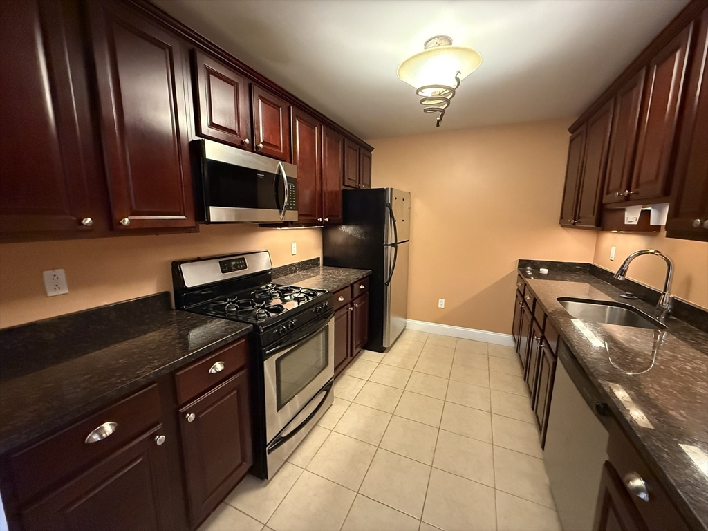 40 Heather Street, Unit 204 Beverly, MA 01915 - Photo 6 of 39 a kitchen with granite countertop a stove and a refrigerator
