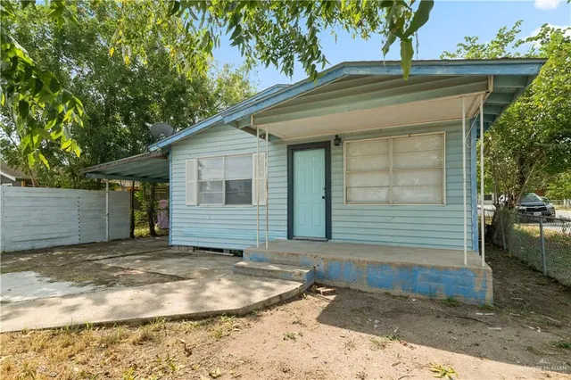 a view of a house with a small yard and large tree