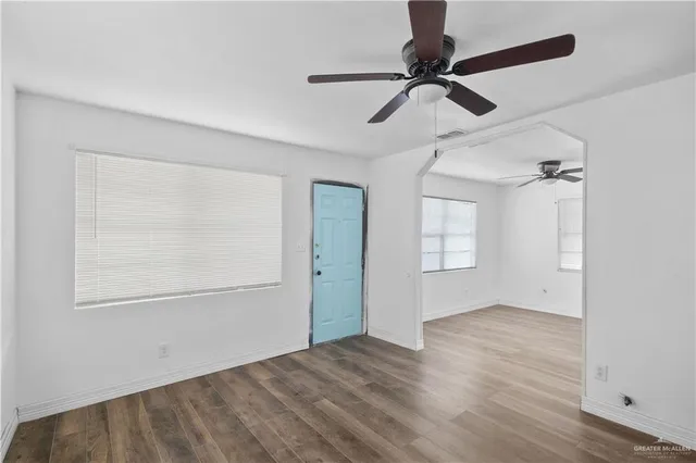 a view of empty room with wooden floor and fan