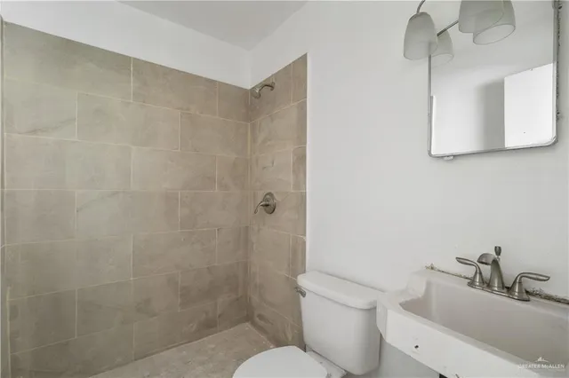 a bathroom with a toilet a sink a mirror and shower