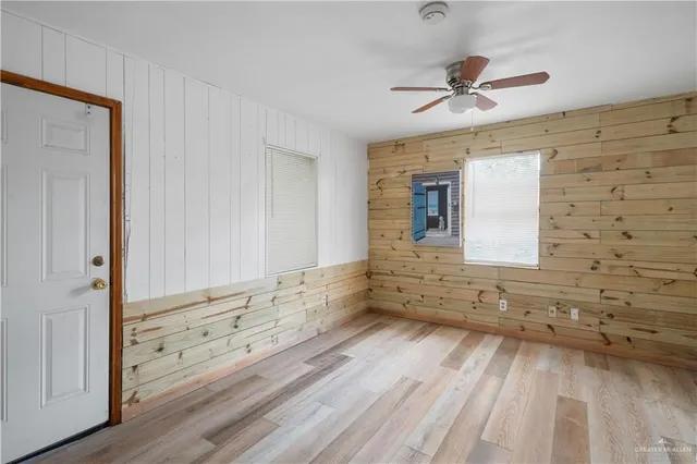 a view of empty room with wooden floor and fan
